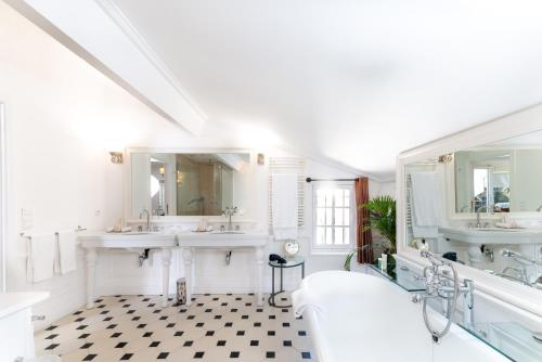 a bathroom with two sinks and two mirrors at Hotel Le Saint Paul in Saint-Paul-de-Vence
