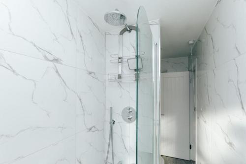 a shower in a bathroom with white marble walls at Propeller house in Wargrave