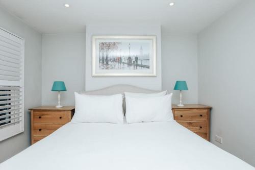 a white bedroom with a white bed and two lamps at Propeller house in Wargrave