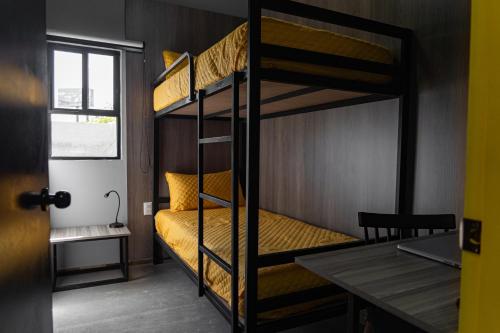 a bunk bed room with two bunk beds and a table at CHECK INN HOSTAL AEROPUERTO GDL in Guadalajara