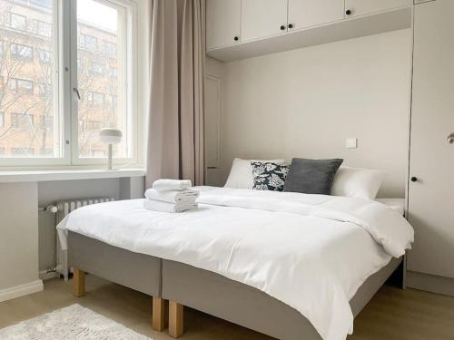 a white bedroom with a large bed with a window at Central 1BR next to the park in Helsinki