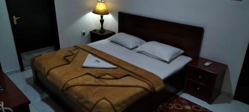 una camera da letto con un letto con una coperta marrone di PAN EMIRATES HOTEL APARTMENTS a Sharjah
