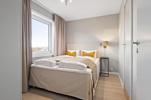 a bedroom with a bed with yellow pillows and a window at Bjørvika Apartments - Sirkus Renaa in Stavanger