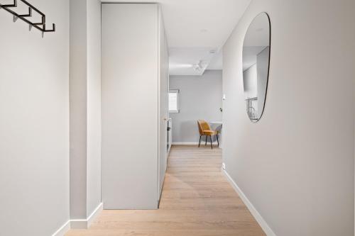 a hallway with white walls and a mirror on the wall at Bjørvika Apartments - Sirkus Renaa in Stavanger