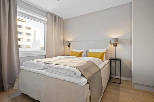 a white bedroom with a large bed with yellow pillows at Bjørvika Apartments - Sirkus Renaa in Stavanger