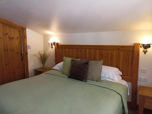 a bedroom with a green bed with two pillows at The Gwaelod y Garth Inn in Cardiff