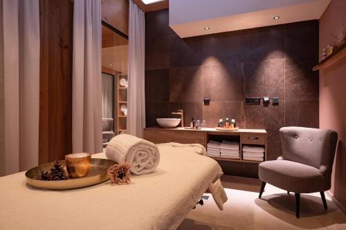 a bathroom with a bed and a sink and a chair at Hotel Pollux in Zermatt