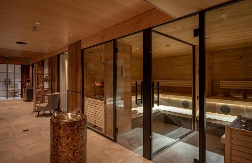 Habitación grande con paredes de cristal y bañera. en Hotel Pollux, en Zermatt