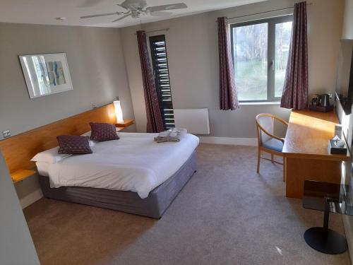 een slaapkamer met een bed, een bureau en een raam bij Roffey Park Institute in Horsham