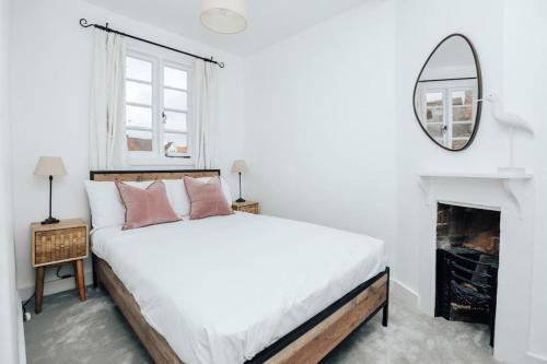een witte slaapkamer met een bed en een open haard bij Chalk house - Pet friendly in Henley on Thames