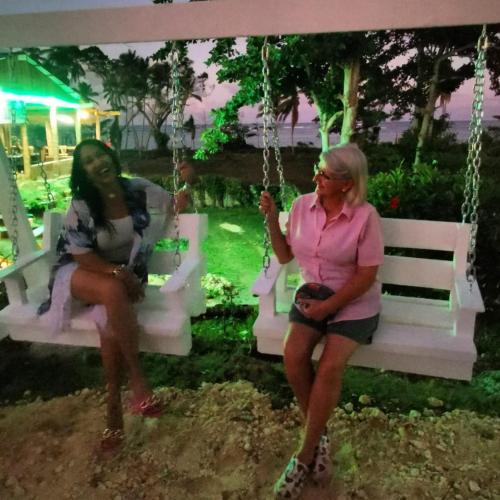 two women sitting on swings in a park at Arena Oceanview Hotel & La Terraza Restaurant in Las Galeras