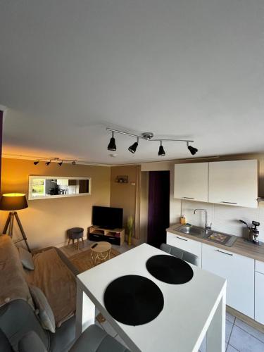 uma cozinha e uma sala de estar com uma mesa branca em Maison confortable et bien équipée entre Caen et Bayeux, proche plages du débarquement em Loucelles