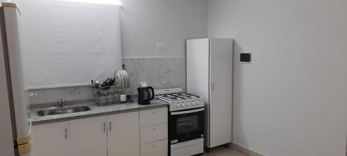 y cocina con fogones, fregadero y nevera. en COMPLEJO COMECHINGONES DPTO 3 2 HABITACIONES en Villa General Belgrano