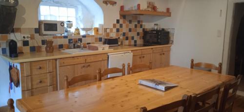 Il comprend une cuisine avec une table en bois et un comptoir. dans l'établissement Maison de Madeleine, à Montpezat-sous-Bauzon