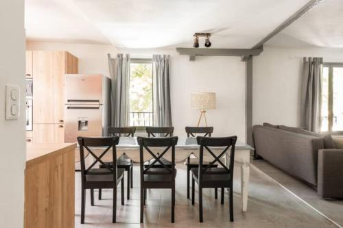 uma cozinha com uma mesa e cadeiras e um sofá em Le marronnier 1 em LʼIsle-sur-la-Sorgue