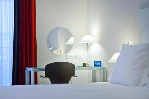 a hotel room with a bed and a chair and a mirror at Hôtel Albe Saint Michel in Paris