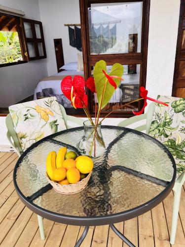 a glass table with a bowl of fruit and a vase of flowers at Cabañas Sentido Ancestral in Jardin