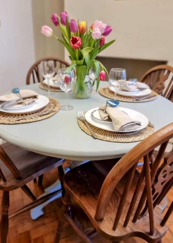 a white table with chairs and a vase of flowers at Cute Cottage in Egham Heathrow- 7 Guests 3 bedrooms in Egham