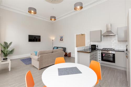 a kitchen and living room with a white table and chairs at Southside Apartments by Destination Edinburgh in Edinburgh