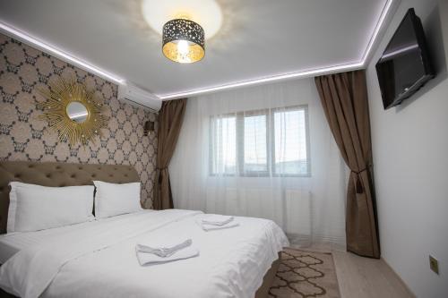 una camera con letto, lenzuola bianche e TV di Apartament Gold a Tîrgu Ocna