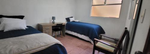 a bedroom with two beds and a desk with a mirror at Casa para viajes de descanso o de negocios in Quetzaltenango