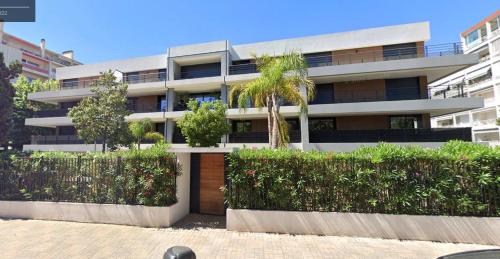 un grand bâtiment avec des buissons devant lui dans l'établissement STUDIO avec terrasse 400m Croisette / Rue d’Antibes, à Cannes