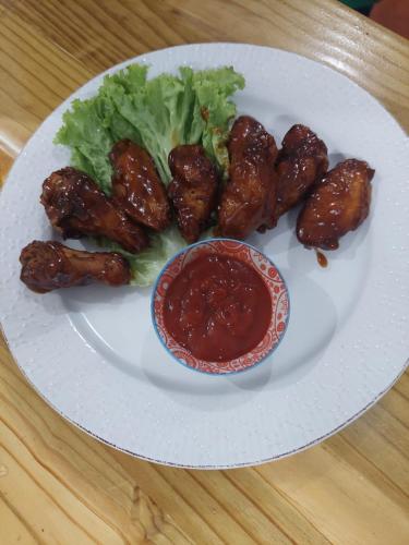 a plate of food with chicken wings and a salad at Arena Oceanview Hotel & La Terraza Restaurant in Las Galeras