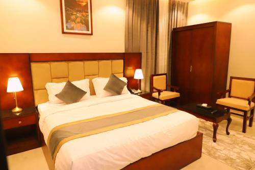 una habitación de hotel con una cama grande y una silla en فندق الأفنيوز بالرس en Al Rass