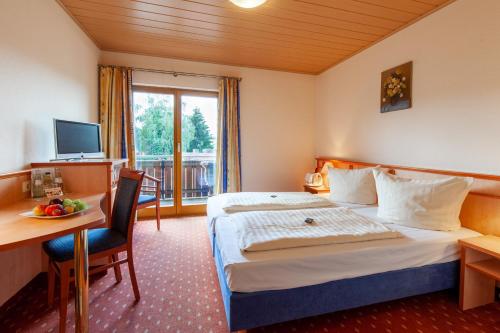 ein Hotelzimmer mit einem Bett, einem Schreibtisch und einem TV in der Unterkunft Landgasthof 'Zur Quelle' in Wächtersbach