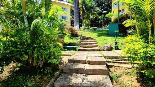 a stone path in a garden with trees and a building at Relax on the Ridge - Ocho Rios Escape in Ocho Rios