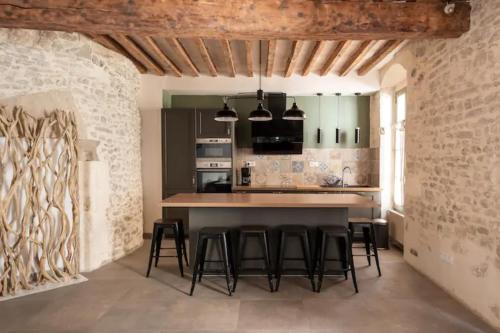 une cuisine avec un comptoir et des tabourets dans une pièce dans l'établissement La Tour 1 Appartement au coeur du centre ville, à LʼIsle-sur-la-Sorgue