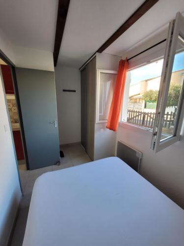 a bedroom with a white bed and a window at Comme à la maison in Marseillan