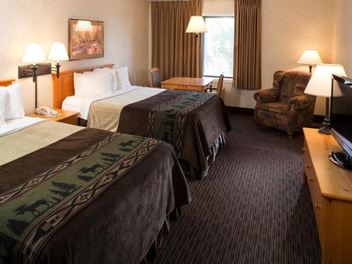 a hotel room with two beds and a chair at Kelly Inn and Suites Mitchell in Mitchell