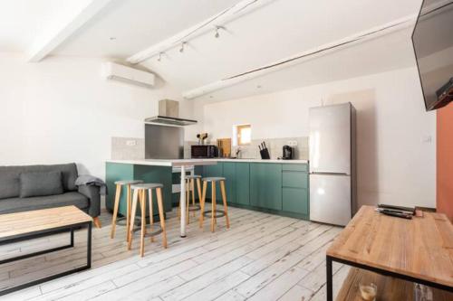 een keuken en een woonkamer met een bank en een koelkast bij Le marronnier 2 in LʼIsle-sur-la-Sorgue