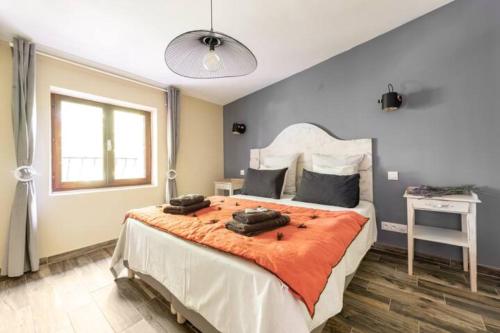 een slaapkamer met een groot bed en een oranje deken bij Le marronnier 2 in LʼIsle-sur-la-Sorgue