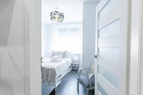 a white bedroom with a bed and a window at Daisy's Secret Apartment in Pszczyna