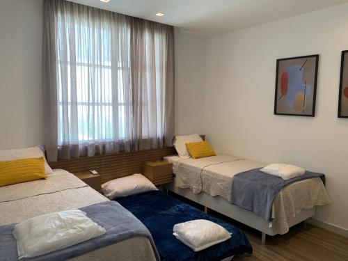 una stanza con tre letti e una finestra di Casa 09 Floresta Boa Vista - Piscina Privativa, Jardim e Lazer Completo a Teresópolis