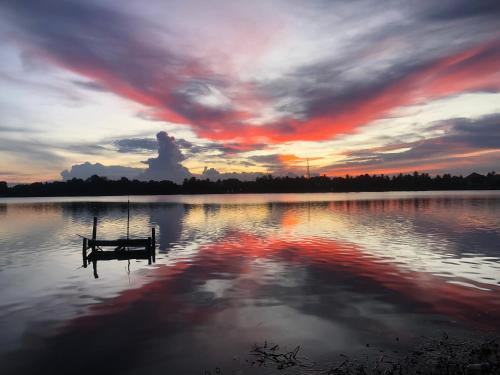 a sunset on a lake with a dock in the water at Lagoon Breeze Resort in Batticaloa