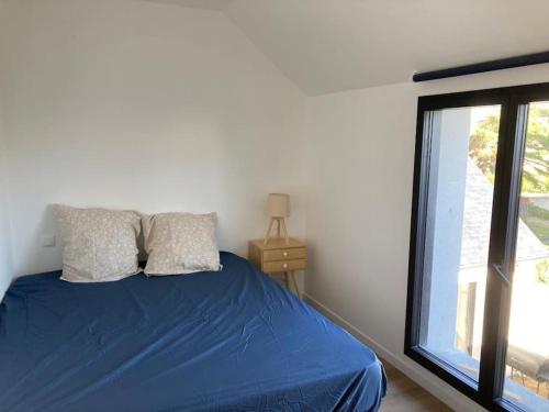 a bedroom with a blue bed with a window at Maison neuve spacieuse port et plages à pied in Ploudalmézeau