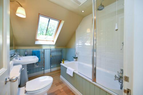 a bathroom with a tub and a toilet and a sink at Stables Cottage in Stranraer