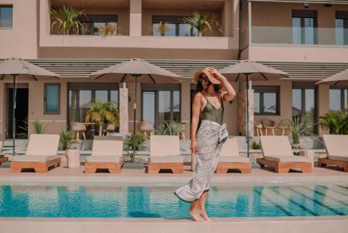 a woman standing next to a swimming pool at Marble Luxury Suites in Karteros