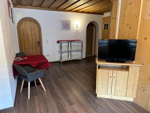 a living room with a television and a table with a chair at Hotel Schwarzer Adler in Pettneu am Arlberg