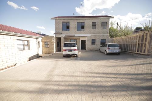 a white van parked in a parking lot in front of a house at The Stone Guest House in Teyateyaneng