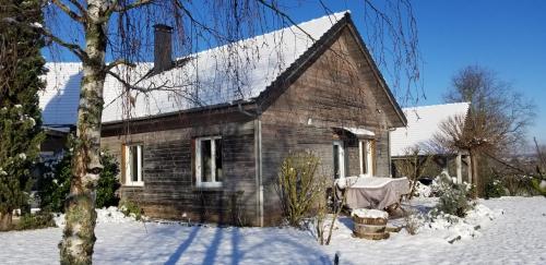 an old wooden house with snow on the ground at Gîte de la Tuillère, maison contemporaine en bois avec vue et piscine in Saint-Aulaire