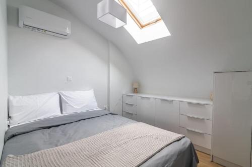 a white bedroom with a bed and a skylight at Μεζονέτα με θέα στο πάρκο Σταύρος Νιάρχος TWO in Athens