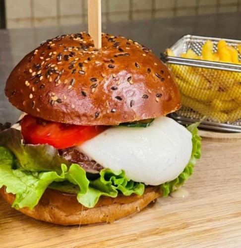 a hamburger with cheese and vegetables on a table at De France by Thermalhotels in Leukerbad