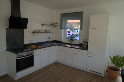 a kitchen with white cabinets and a sink and a window at Dangos Mountainview Gosau in Gosau
