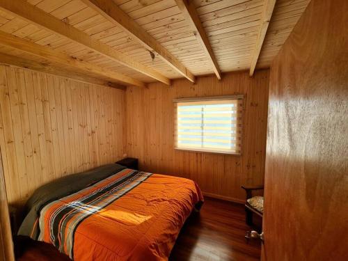 een slaapkamer met een bed in een kamer met een raam bij Acogedora cabaña en Pelluhue a metros de la playa in Pelluhue