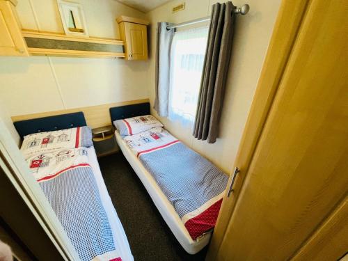 two beds in a small room with a window at 3 Bedroom Caravan KG37, Dog Friendly, Shanklin, Isle of Wight in Shanklin