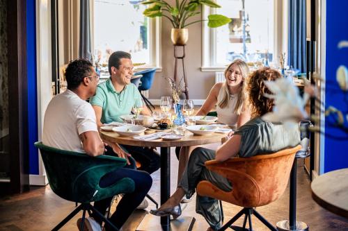 een groep mensen die rond een tafel in een restaurant zitten bij Hotel de Wereld in Wageningen